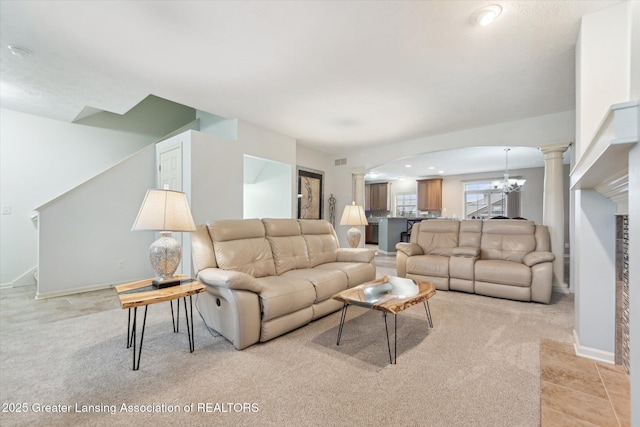 living room featuring light carpet, a notable chandelier, arched walkways, and decorative columns