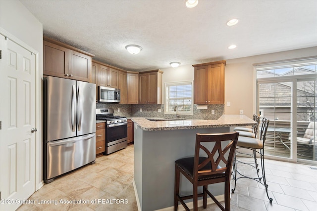 kitchen featuring backsplash, a breakfast bar, a peninsula, and appliances with stainless steel finishes