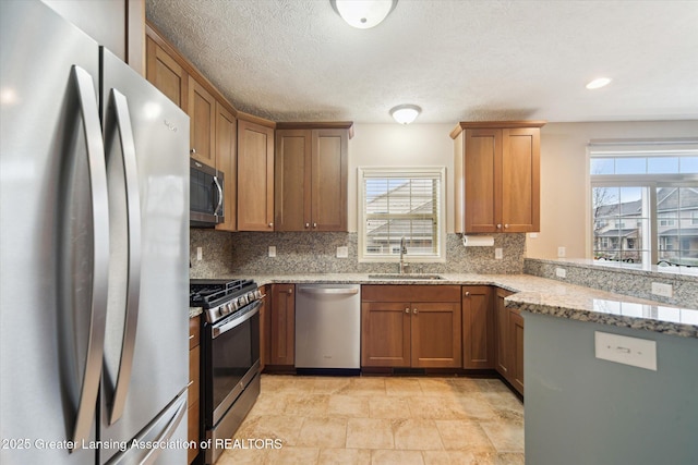 kitchen featuring light stone countertops, a sink, appliances with stainless steel finishes, and decorative backsplash
