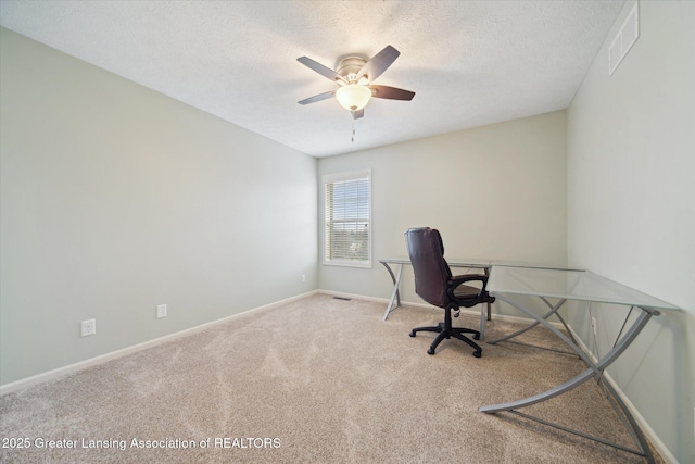 carpeted home office featuring a ceiling fan, visible vents, a textured ceiling, and baseboards