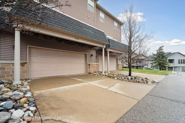 view of front of home featuring concrete driveway, stone siding, and a garage