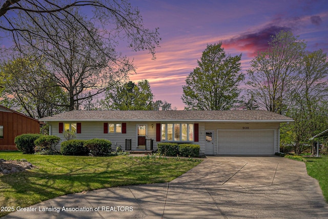 ranch-style home featuring a garage, a yard, and concrete driveway