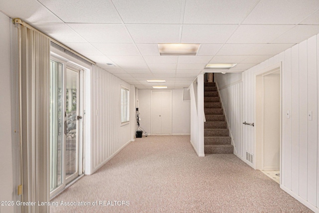 basement featuring visible vents, carpet flooring, a paneled ceiling, and stairs