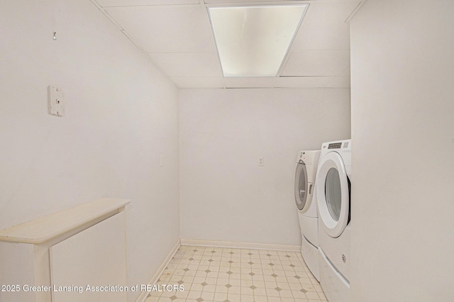 washroom featuring laundry area, baseboards, light floors, and washing machine and dryer