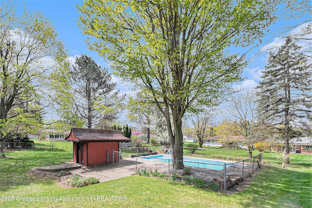 view of yard with a fenced in pool, an outbuilding, fence, and a storage shed
