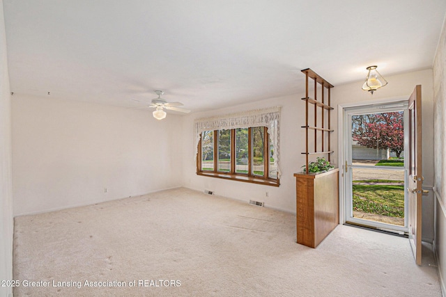 foyer featuring visible vents, carpet, a ceiling fan, and a wealth of natural light