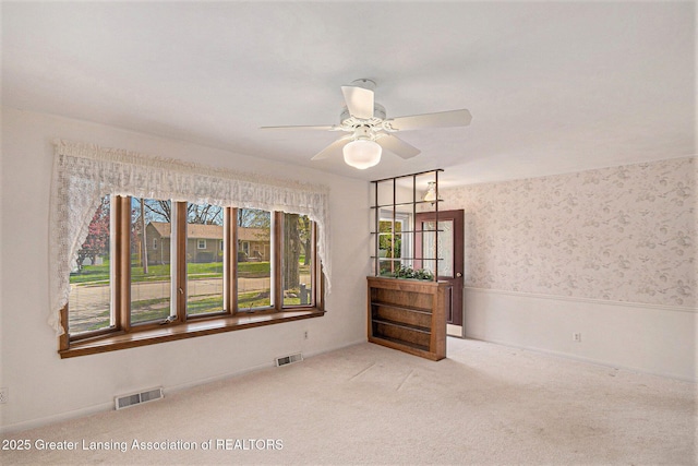 spare room with visible vents, carpet flooring, and a ceiling fan