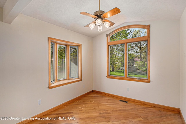 spare room with baseboards, a ceiling fan, light wood-style flooring, and lofted ceiling