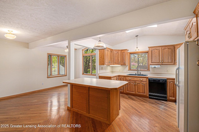 kitchen featuring a sink, light countertops, freestanding refrigerator, and dishwasher