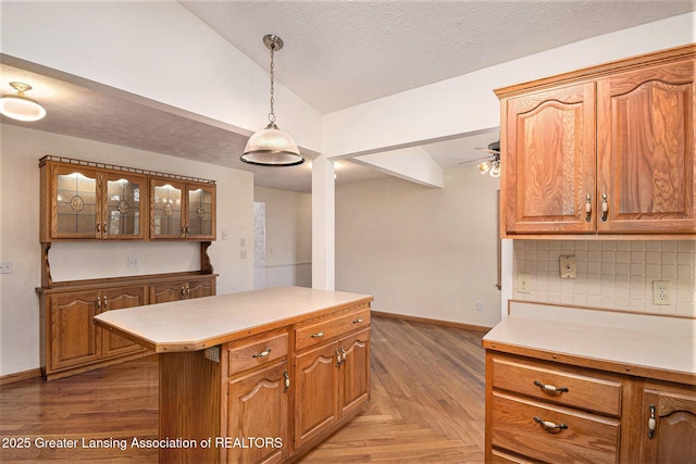 kitchen with light countertops, baseboards, backsplash, and lofted ceiling