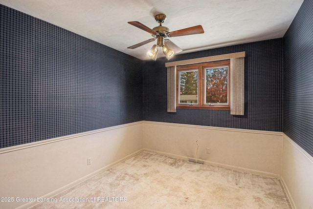 carpeted empty room with baseboards, a ceiling fan, wallpapered walls, and visible vents