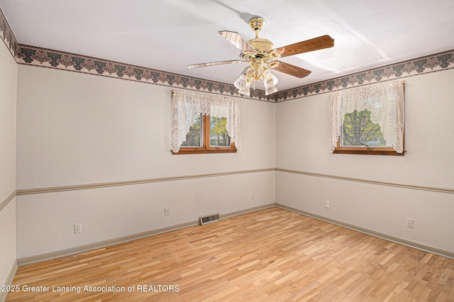 spare room featuring baseboards, ceiling fan, wood finished floors, and visible vents