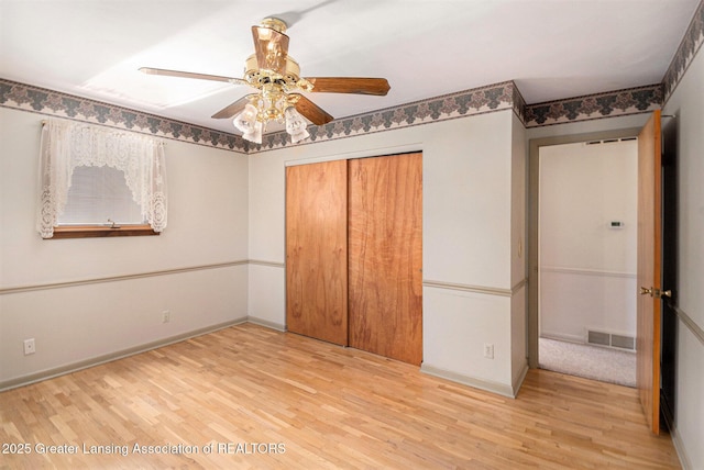 unfurnished bedroom featuring baseboards, visible vents, wood finished floors, and a closet