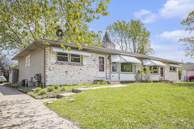 601/603 Farmstead Ln, Lansing, MI 48917 - view of front facade with a chimney, a front yard, cooling unit, and brick siding
