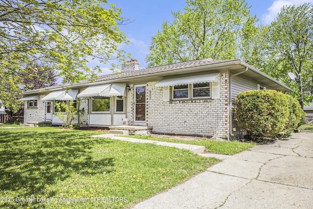 601/603 Farmstead Ln, Lansing, MI 48917 - view of front of property featuring a chimney, a front lawn, and brick siding