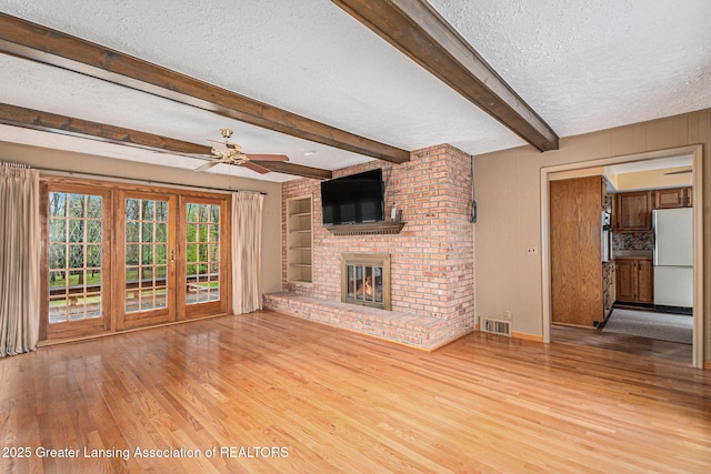 6528 Old River Trl, Lansing, MI 48917 - unfurnished living room featuring a ceiling fan, a textured ceiling, visible vents, wood finished floors, and a fireplace