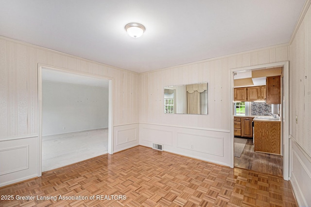 6528 Old River Trl, Lansing, MI 48917 - empty room with a sink, ornamental molding, a decorative wall, and visible vents