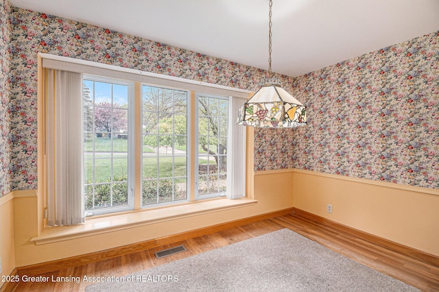 6528 Old River Trl, Lansing, MI 48917 - unfurnished dining area with baseboards, visible vents, wallpapered walls, and wood finished floors