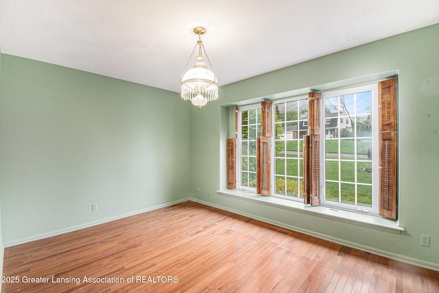 6528 Old River Trl, Lansing, MI 48917 - empty room featuring a chandelier, baseboards, and wood-type flooring