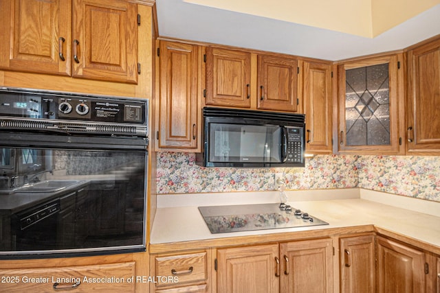 6528 Old River Trl, Lansing, MI 48917 - kitchen with light countertops, black appliances, glass insert cabinets, and brown cabinets