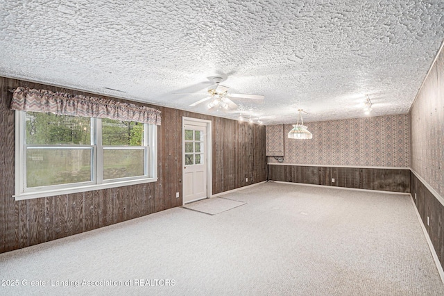 6528 Old River Trl, Lansing, MI 48917 - carpeted empty room featuring wallpapered walls, a textured ceiling, wooden walls, and ceiling fan