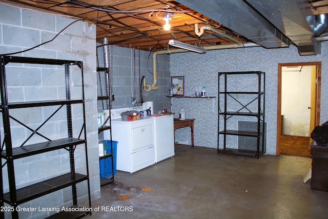unfinished below grade area with concrete block wall and washing machine and dryer