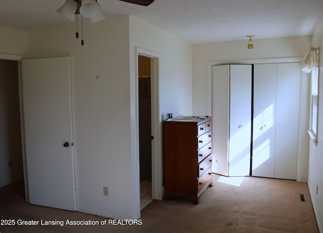 unfurnished bedroom featuring visible vents, a closet, ceiling fan, and light colored carpet