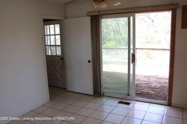 doorway with ceiling fan and light tile patterned flooring