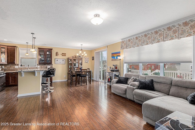 living area featuring an inviting chandelier, a textured ceiling, dark wood finished floors, and baseboards