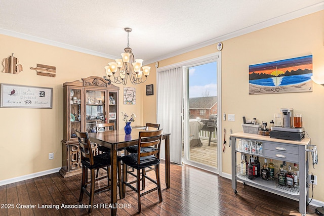 dining space with dark wood finished floors, baseboards, ornamental molding, and an inviting chandelier