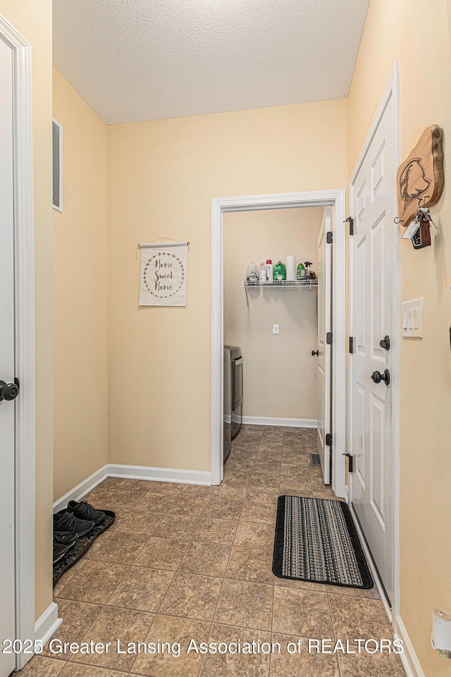 interior space featuring baseboards, a textured ceiling, laundry area, and washing machine and dryer