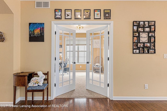 entryway with baseboards, visible vents, and wood-type flooring