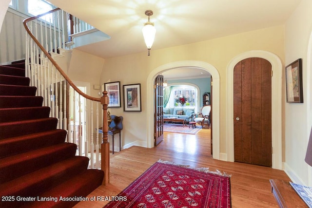 620 Ardson Rd, East Lansing, MI 48823 - foyer entrance featuring arched walkways, wood finished floors, stairway, and baseboards