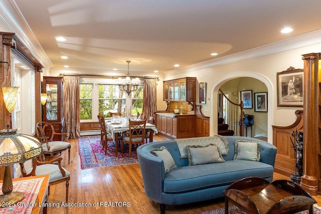 620 Ardson Rd, East Lansing, MI 48823 - living room with crown molding, light wood finished floors, a chandelier, arched walkways, and baseboard heating