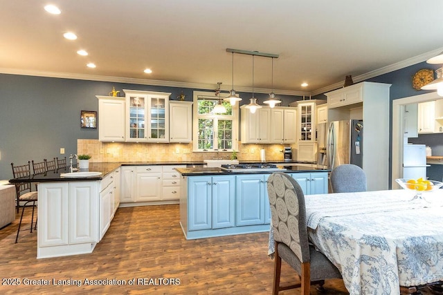 620 Ardson Rd, East Lansing, MI 48823 - kitchen featuring a peninsula, dark countertops, a center island, a breakfast bar, and decorative backsplash