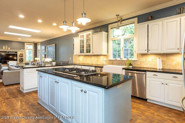 620 Ardson Rd, East Lansing, MI 48823 - kitchen featuring stainless steel appliances, dark countertops, ornamental molding, open floor plan, and a center island