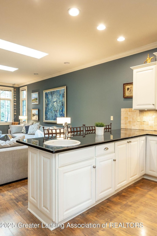620 Ardson Rd, East Lansing, MI 48823 - kitchen with a sink, ornamental molding, dark countertops, white cabinetry, and wood finished floors
