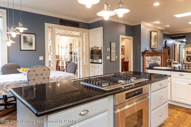620 Ardson Rd, East Lansing, MI 48823 - kitchen featuring stainless steel gas cooktop, a center island, white cabinetry, a sink, and wood finished floors