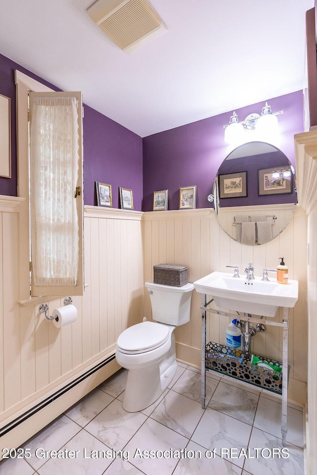 620 Ardson Rd, East Lansing, MI 48823 - bathroom featuring a baseboard heating unit, marble finish flooring, wainscoting, and toilet