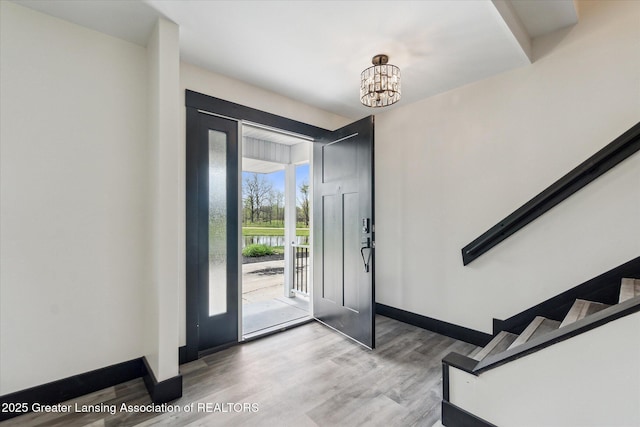 1551 E Lovejoy Rd, Perry, MI 48872 - foyer featuring wood finished floors, baseboards, a chandelier, and stairway