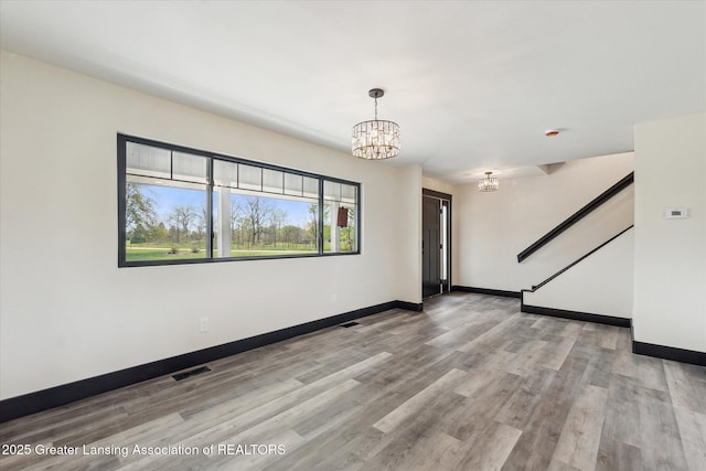1551 E Lovejoy Rd, Perry, MI 48872 - spare room featuring a chandelier, baseboards, light wood-style flooring, and stairs