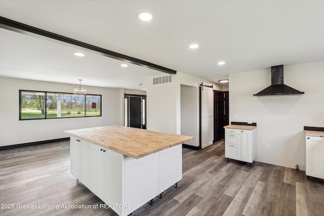 1551 E Lovejoy Rd, Perry, MI 48872 - kitchen featuring wall chimney exhaust hood, wood counters, a barn door, white cabinetry, and light wood-type flooring