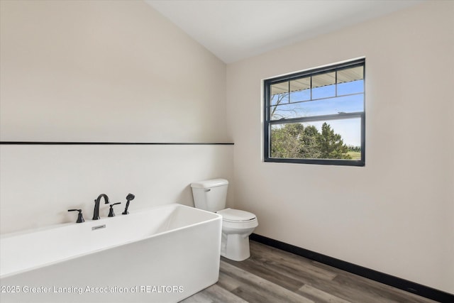 1551 E Lovejoy Rd, Perry, MI 48872 - bathroom with toilet, wood finished floors, a tub to relax in, and baseboards