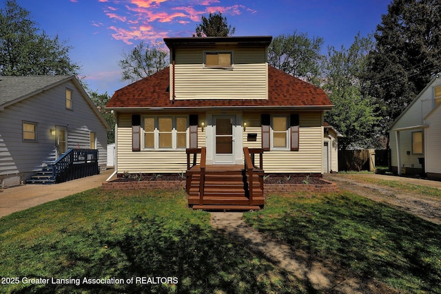 view of front of home with a lawn, a shingled roof, and driveway
