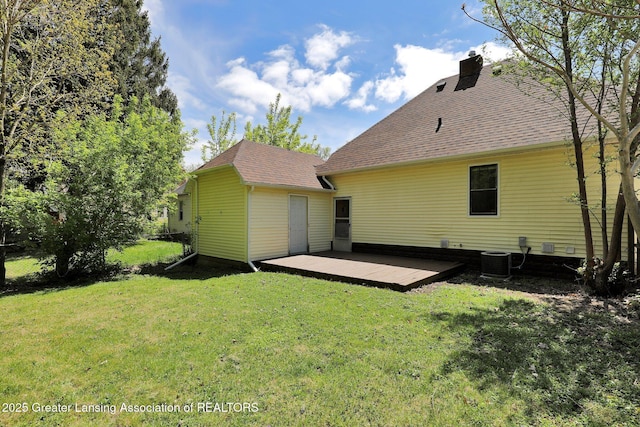 rear view of house with a yard, a wooden deck, central air condition unit, and a shingled roof