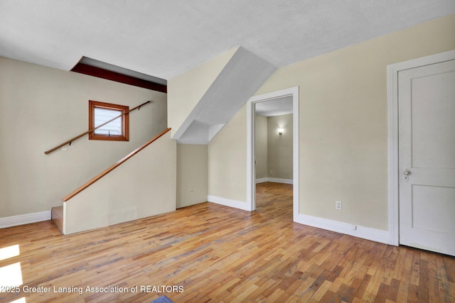 bonus room featuring light wood-type flooring, baseboards, and stairs