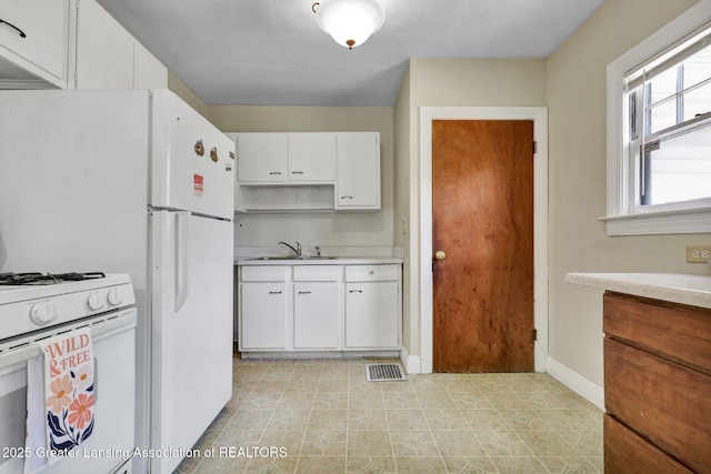 kitchen featuring white range with gas cooktop, light countertops, white cabinetry, a sink, and baseboards