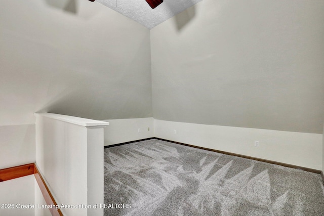 carpeted spare room with ceiling fan, baseboards, and a textured ceiling