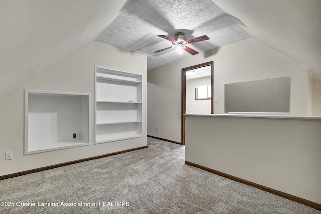 bonus room featuring ceiling fan, lofted ceiling, carpet, baseboards, and built in shelves