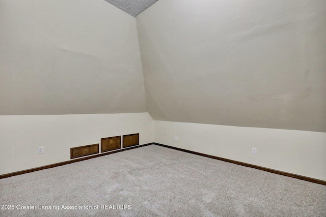 bonus room featuring lofted ceiling, carpet, and baseboards